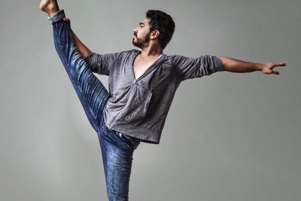 A person performing a controlled yoga movement in a minimalist room.