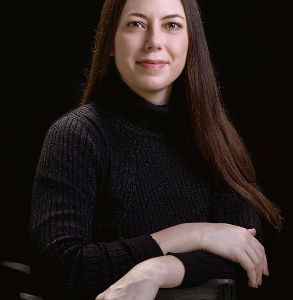 Woman holding a challenging balance pose in a dark studio.